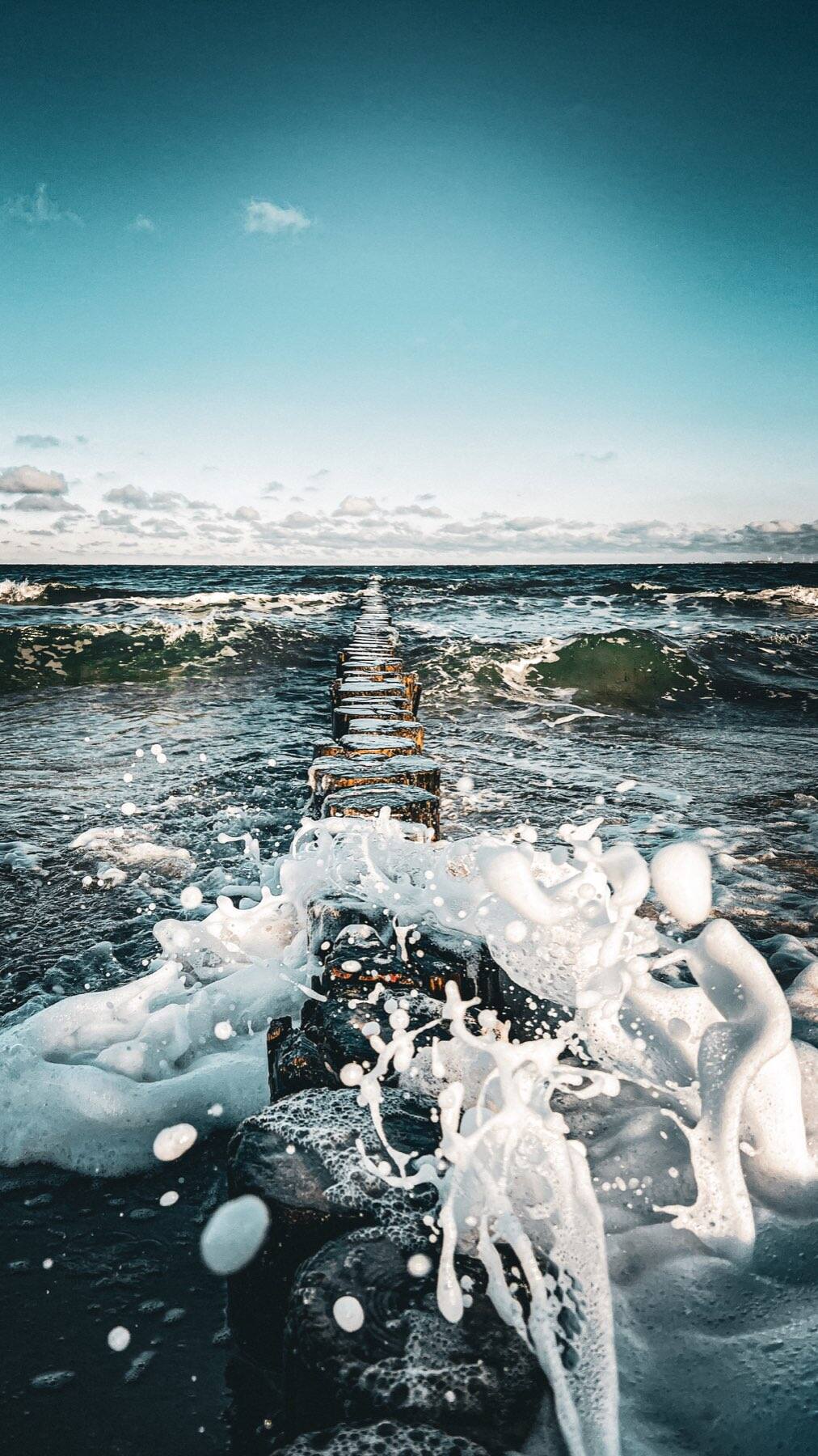 Buhnen ziehen eine Linie in die aufschäumende Ostsee
