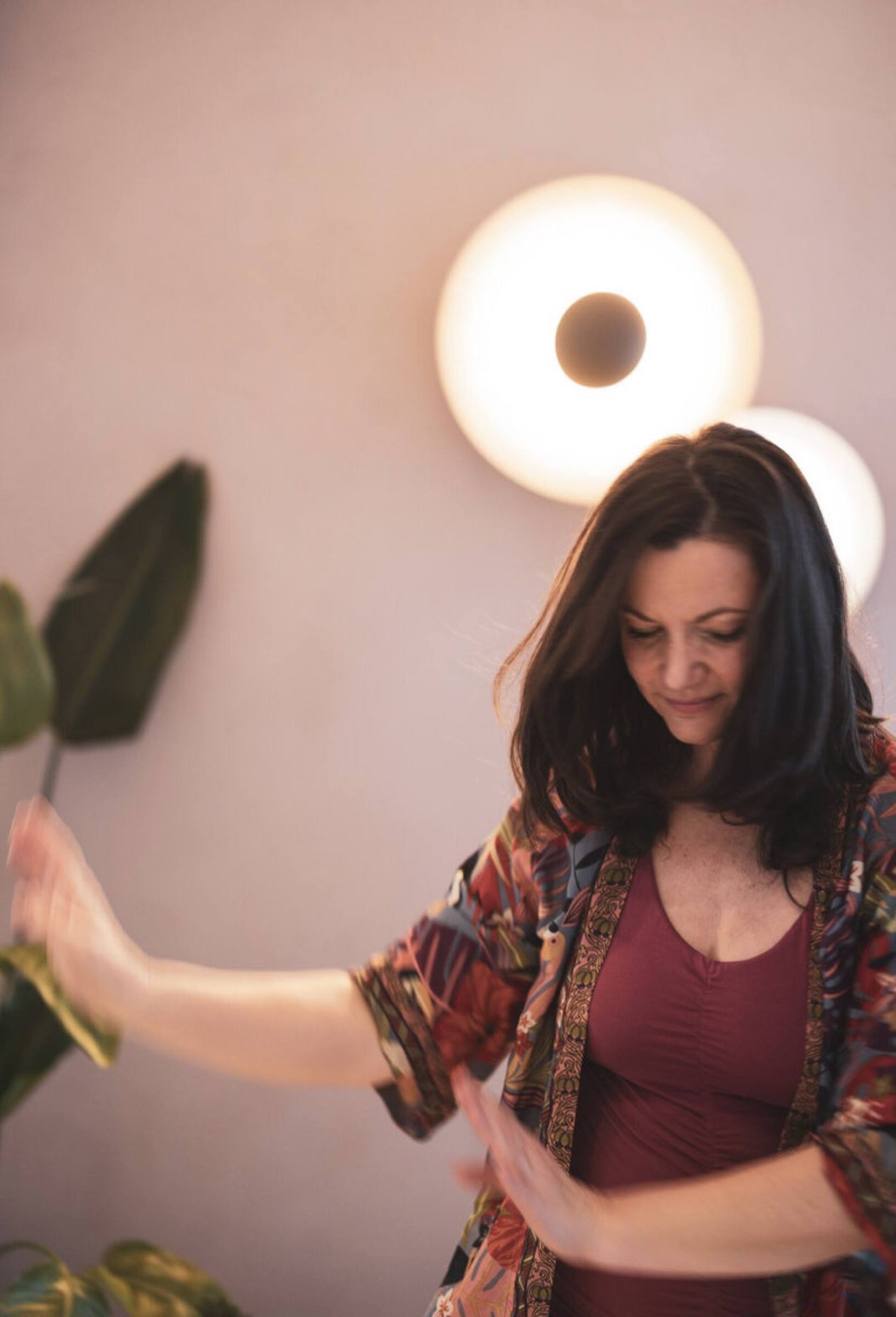 Julia tanzt versunken im warmen Licht ihres Studios, im bunten Blüten-Kimono